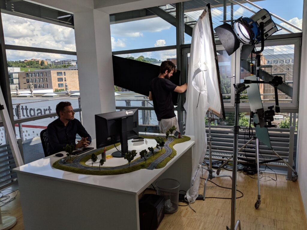 Studio mit Modelllandschaft auf einem Tisch, Kamera, Scheinwerfer und Crew am Rechner