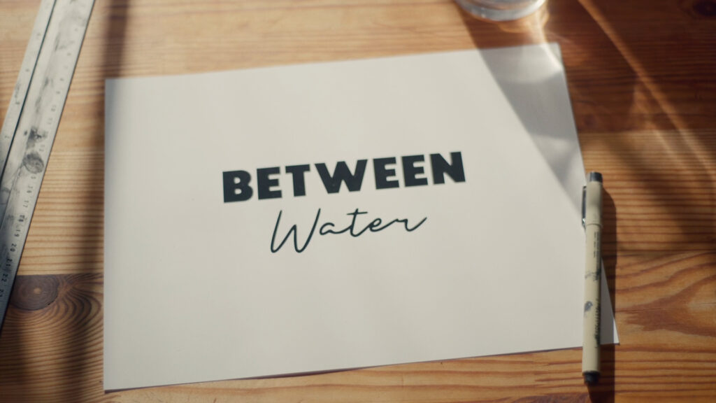 Weiße Karte mit dem Logo von Between Water auf einem Holztisch