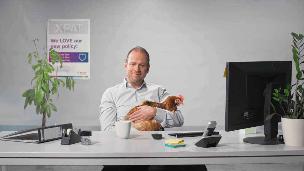 Bosch XPAT, im Büro Mitarbeiter am Schreibtisch mit Monitor und Pflanze, Standbild aus dem Recruitingfilm Bosch XPAT