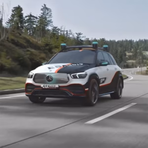 3D Rendering eines Mercedes-Benz SUV mit weiß-schwarzer Lackierung und orangen Akzenten, ausgestattet mit mehreren Sensoren auf dem Dach, fährt auf einer Landstraße mit Wald im Hintergrund.