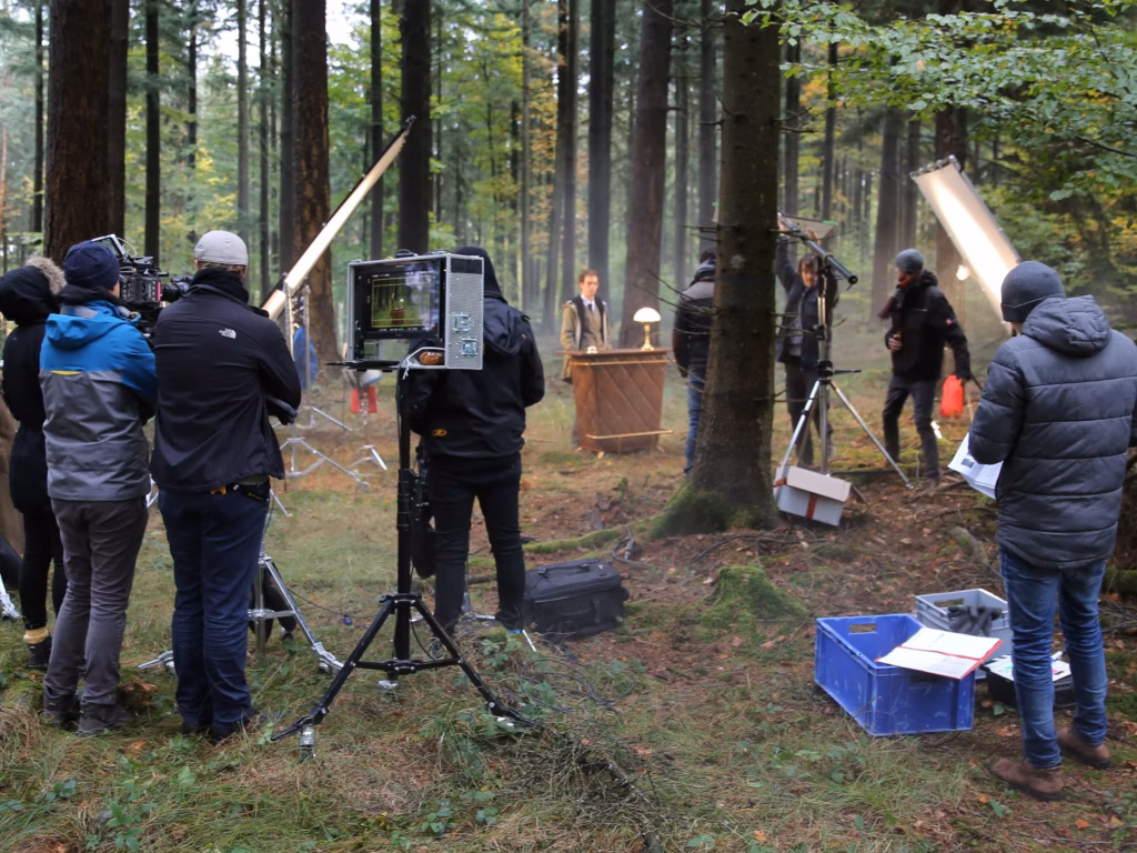 Filmcrew mit Kamera, Monitor und Scheinwerfer beim Dreh im Wald